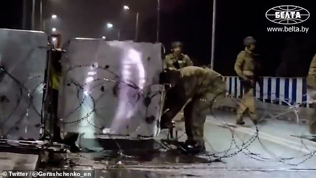 Polish troops pull barbed wire across a road and move barricades to seal the eastern border