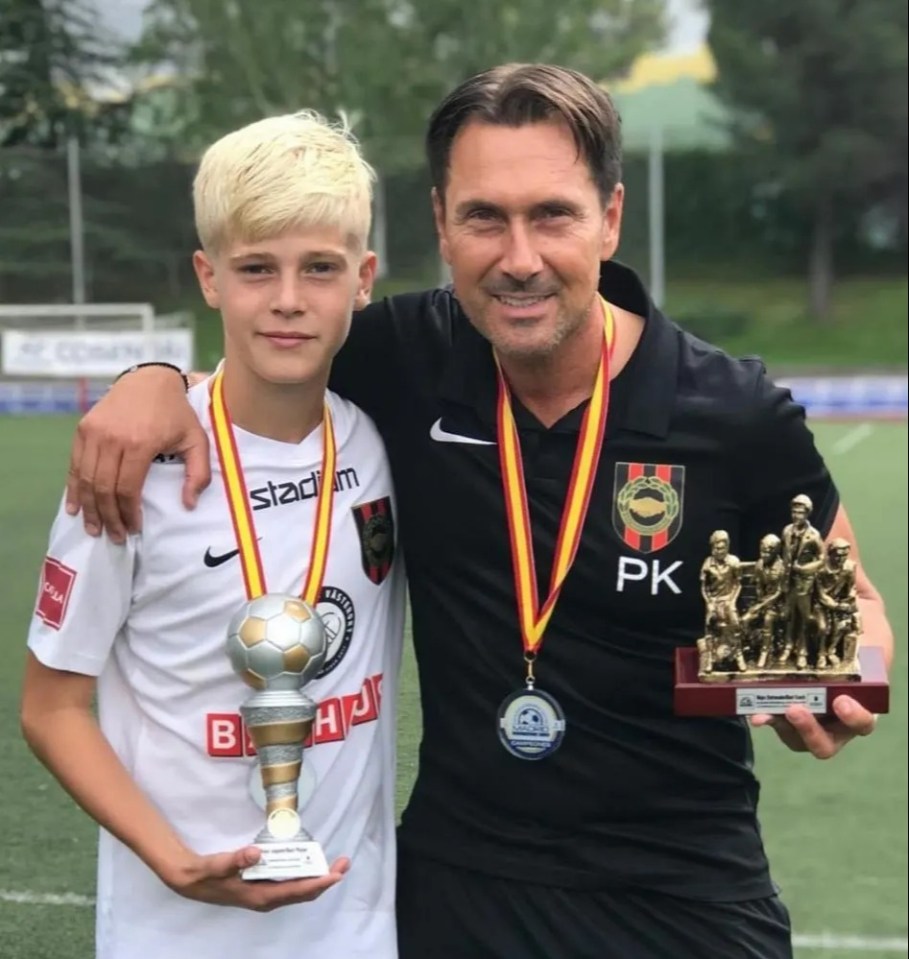 A boy and man holding soccer trophies and medals.
