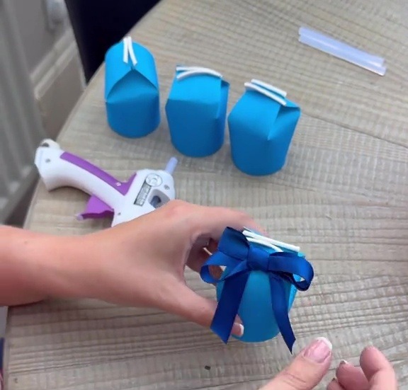 Person making small blue gift boxes.