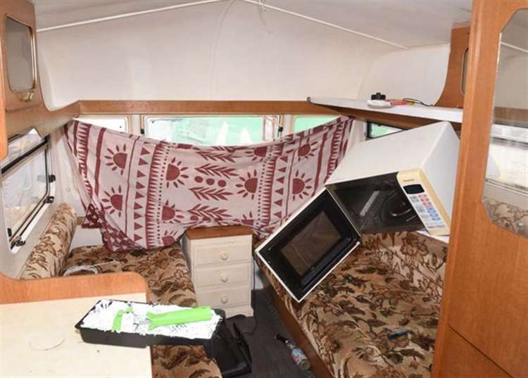 Interior of a caravan with a tipped-over microwave.