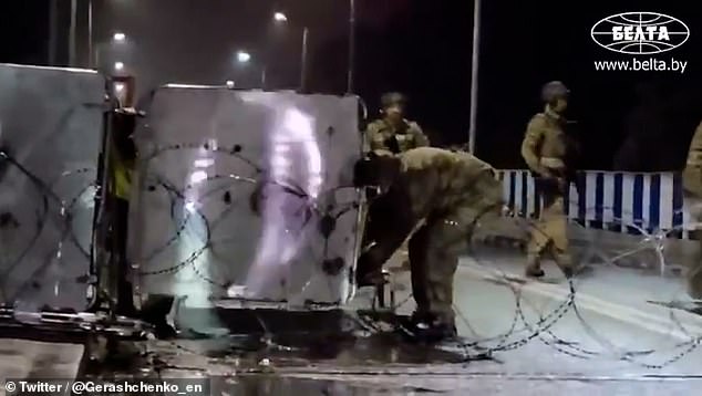 Polish troops pull barbed wire across a road and move barricades to seal the eastern border