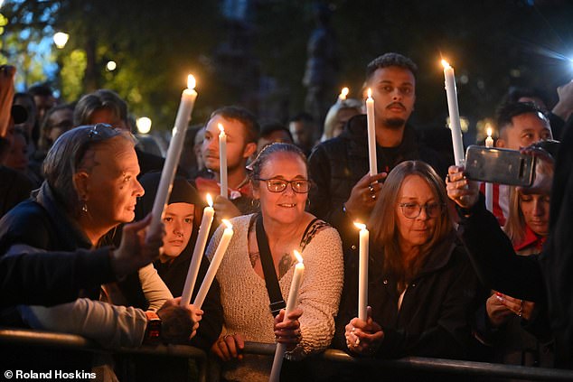 Attendees are pictured here holding up candles as they pay tribute to Charlie Kirk in London on Friday