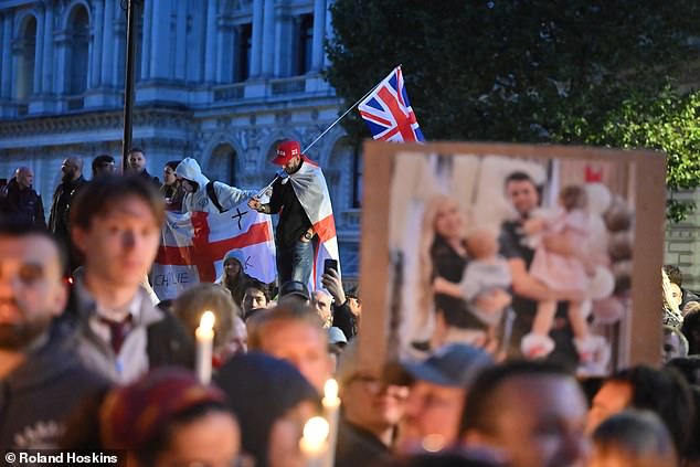 Mourners are pictured here holding up a photo of Kirk with his wife and two children