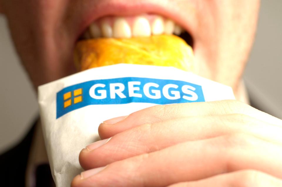 Person eating a Greggs sausage roll.