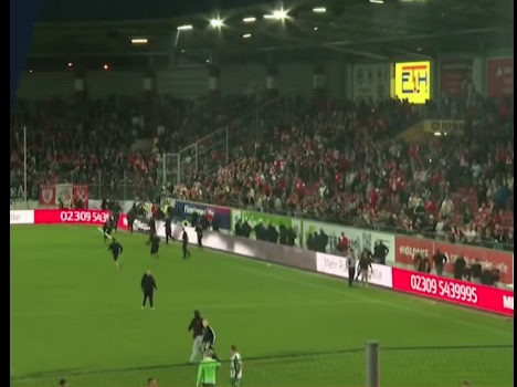 Soccer game with fans in stands and people on the field.