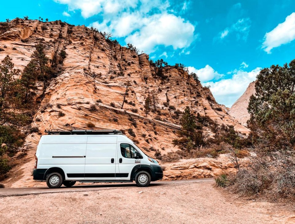 White van parked near a sandstone cliff.