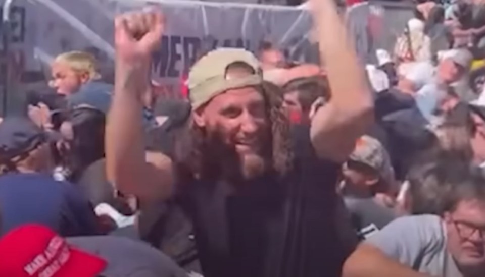 Man with long hair and beard cheering in a crowd.