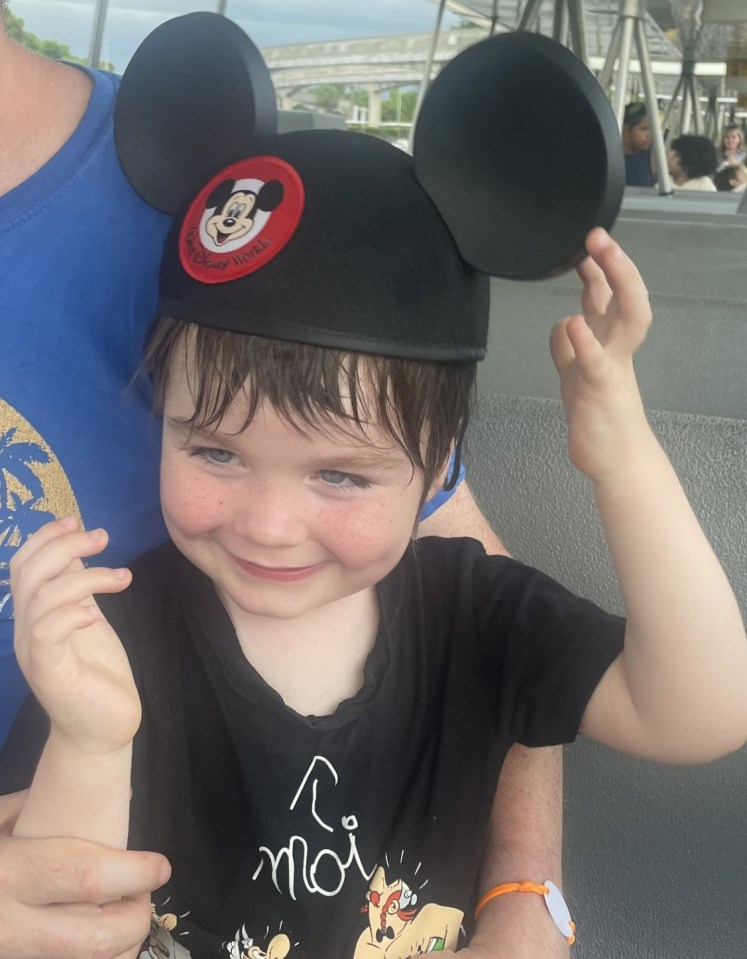 Smiling toddler wearing Mickey Mouse ears.