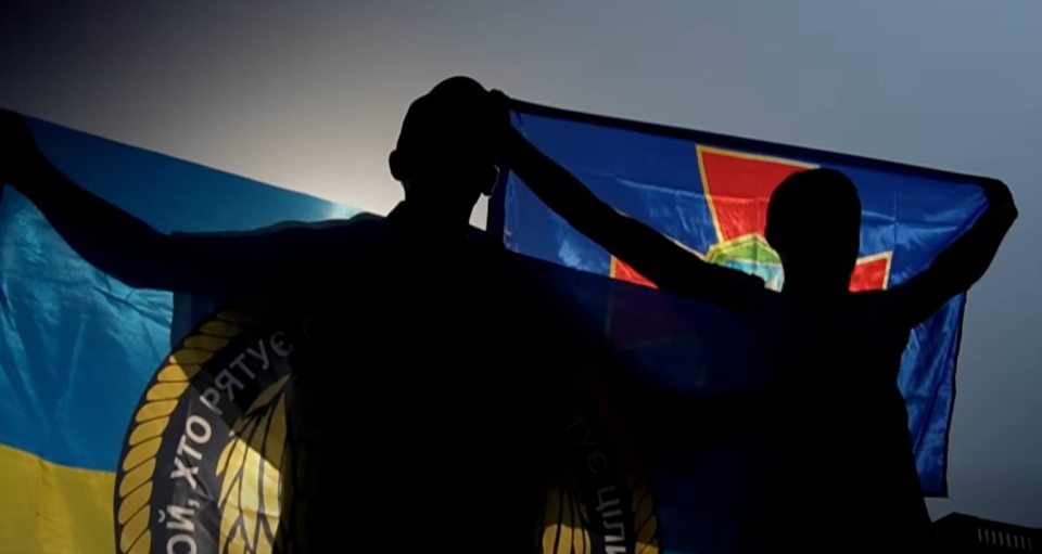 Silhouette of two people holding Ukrainian flags.