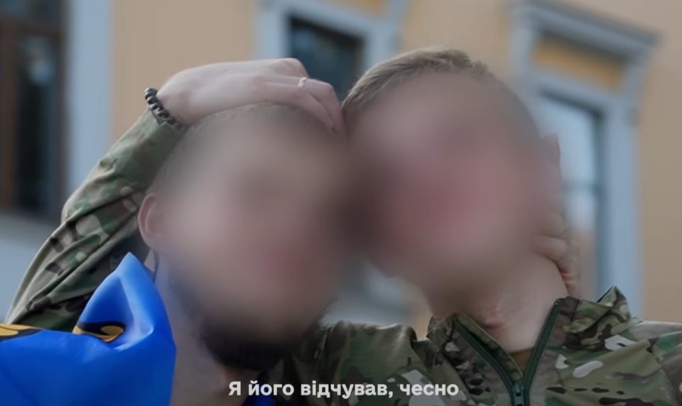 Two blurred faces of people in military uniforms embracing.