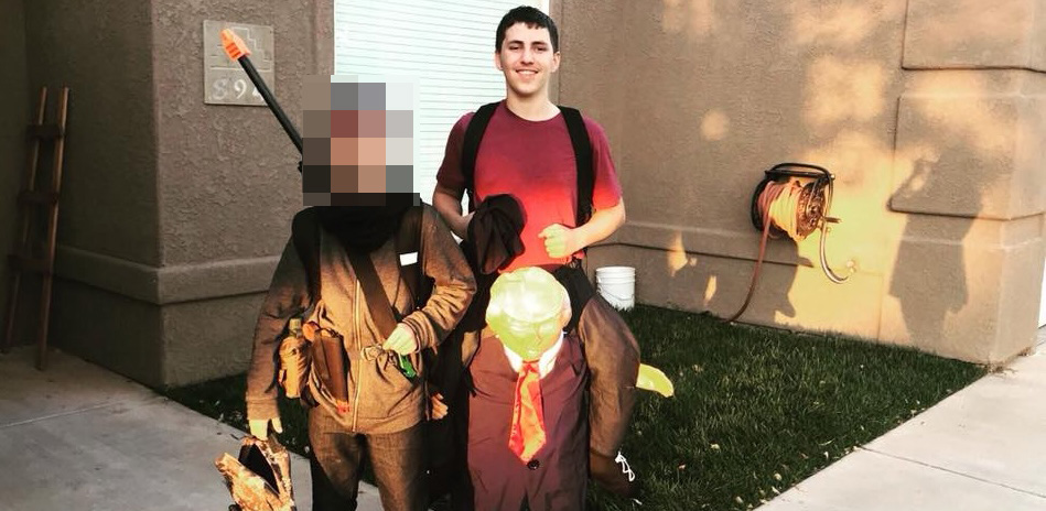 Photo of a man in a red shirt standing with two children in costumes; one child's face is obscured.