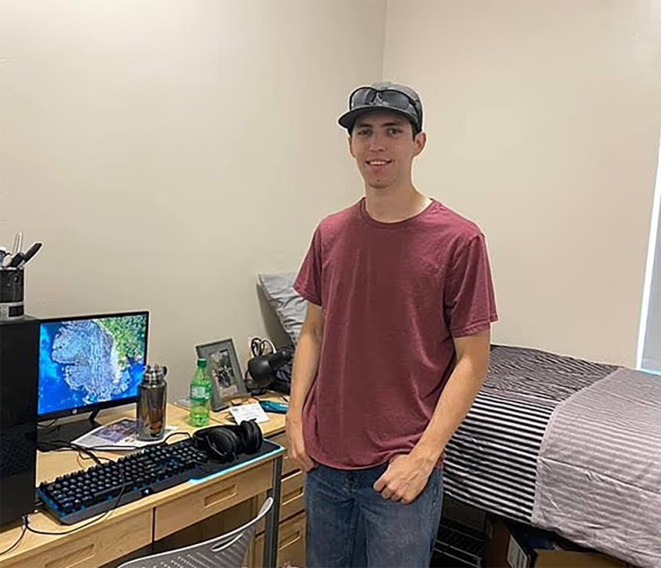 Young man standing in his dorm room.