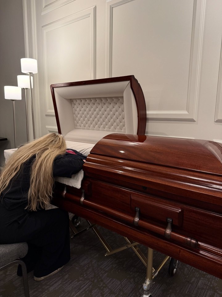 A woman grieving at a coffin.