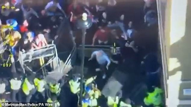 The men made the comments as they stood among the 110,000 activists who had taken to the streets to protest immigration. Pictured: Overhead footage shared by the Met Police showed groups of protesters attempting to force their way through police barriers
