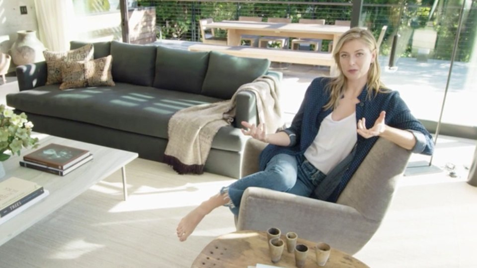 Maria Sharapova sitting in a chair in a modern living room.