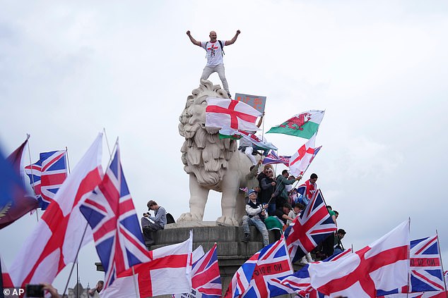 A demonstrator stands on the head of the South Bank lion that sits on the side of the Westminster Bridge, during a Tommy Robinson-led Unite the Kingdom march and rally in London on September 13