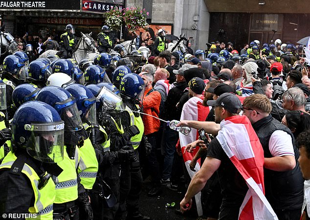 A Unite The Kingdom protester sprays an unknown liquid at a police officer in riot gear