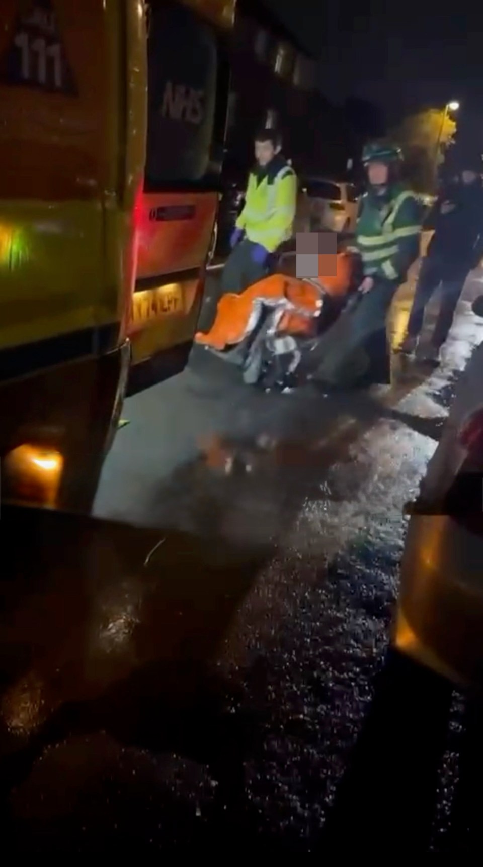 Paramedics loading a casualty into an ambulance after a house explosion.