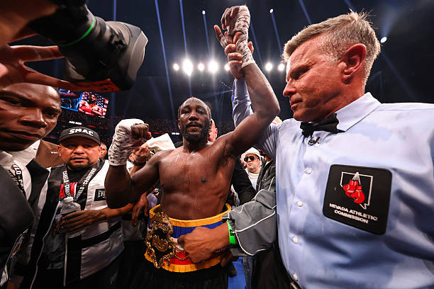 Terence Crawford victorious in boxing match, raising his arm with championship belt.