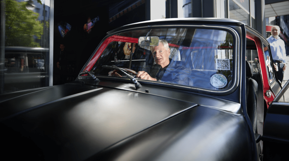 Man driving a black Mini Cooper.