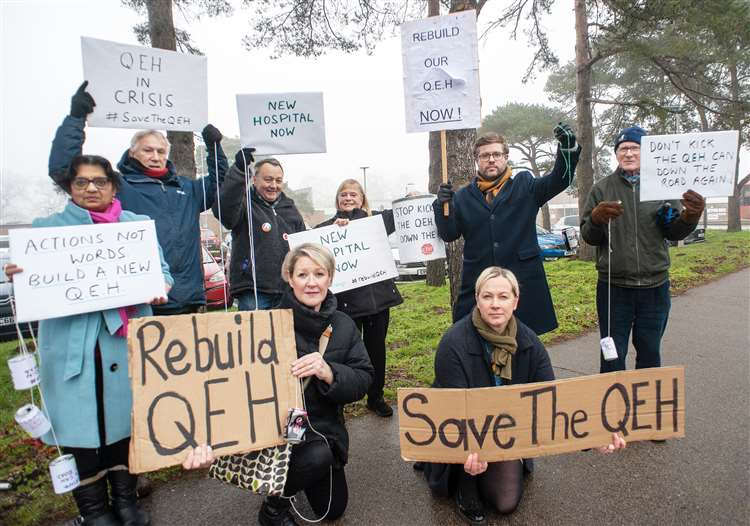 Protestors holding signs advocating for the rebuilding of the QEH hospital.