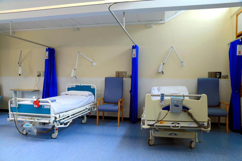 Hospital ward with two beds and chairs.