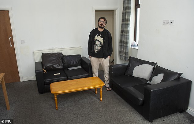 Dere's sparsely-decorated living area has two black two-seater sofas against bare white walls