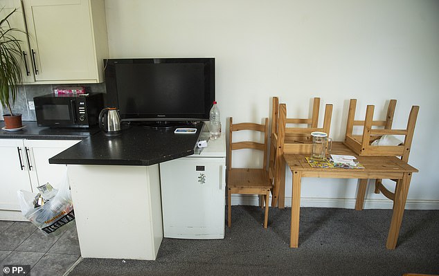 Inside Dere's house is a small dining table and a television perched on his kitchen worktop