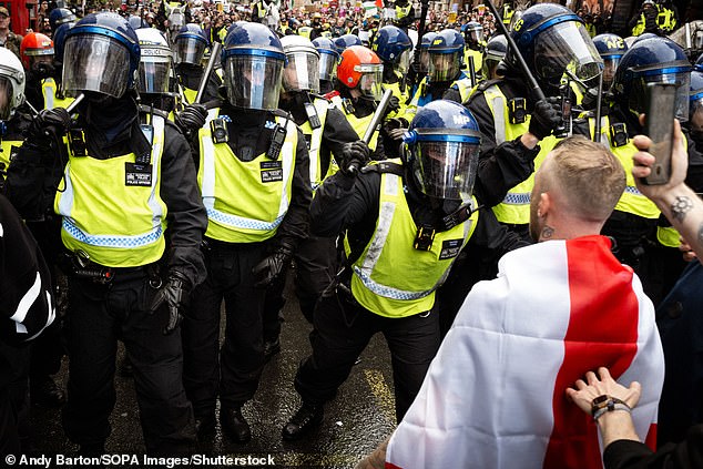 A man draped in an St Georges flag confronts the police cordon which was in place to separate the Unite The Kingdom supporters and counter-protesters