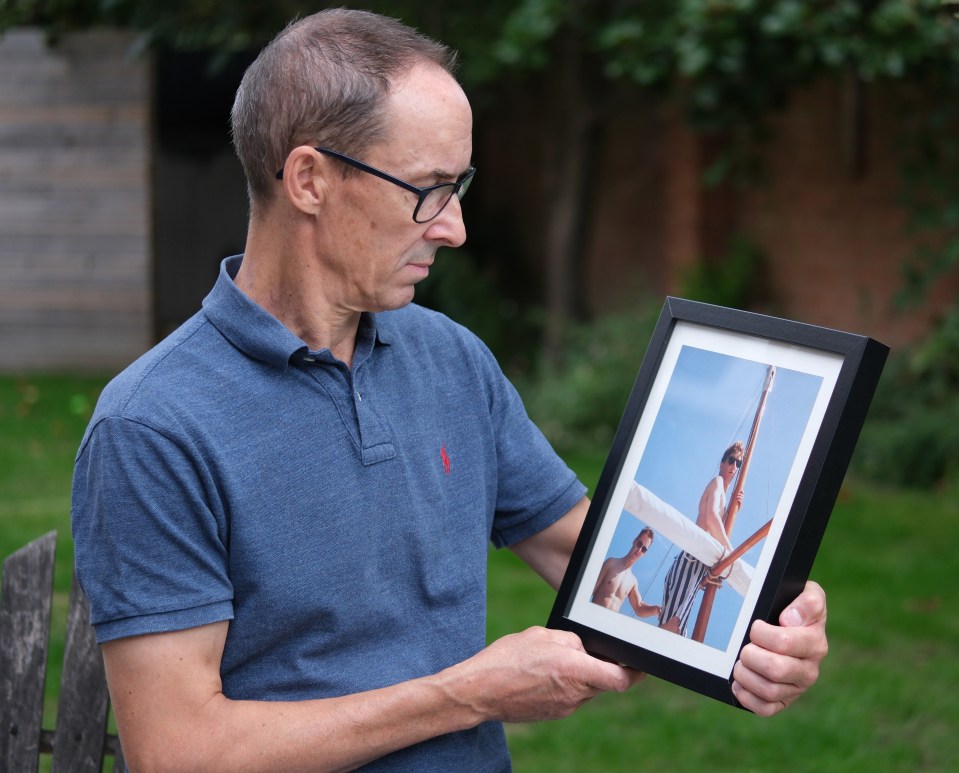 A man holds a framed photo of his murdered twin brother.