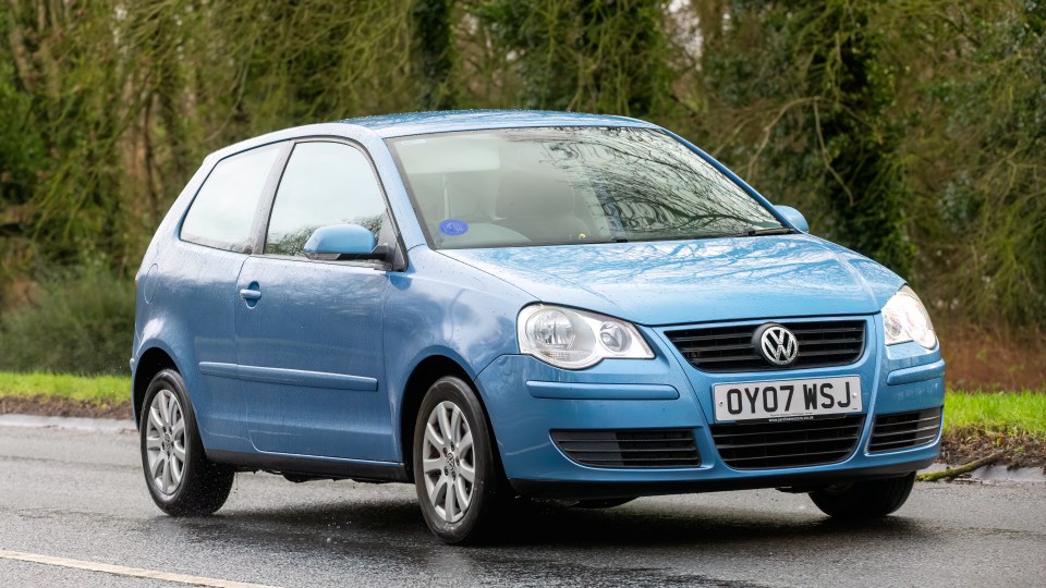 Blue Volkswagen Polo driving on a road.