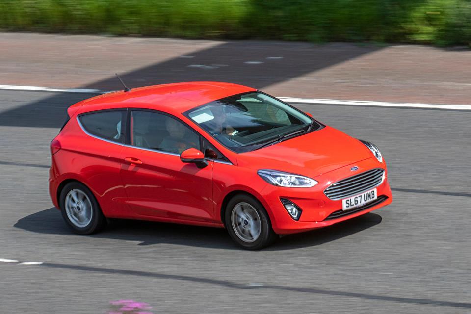 Red Ford Fiesta driving on a highway.