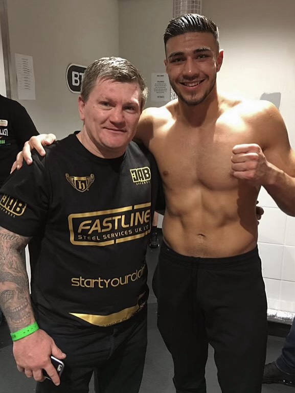 Photo of two men, one shirtless, posing together.