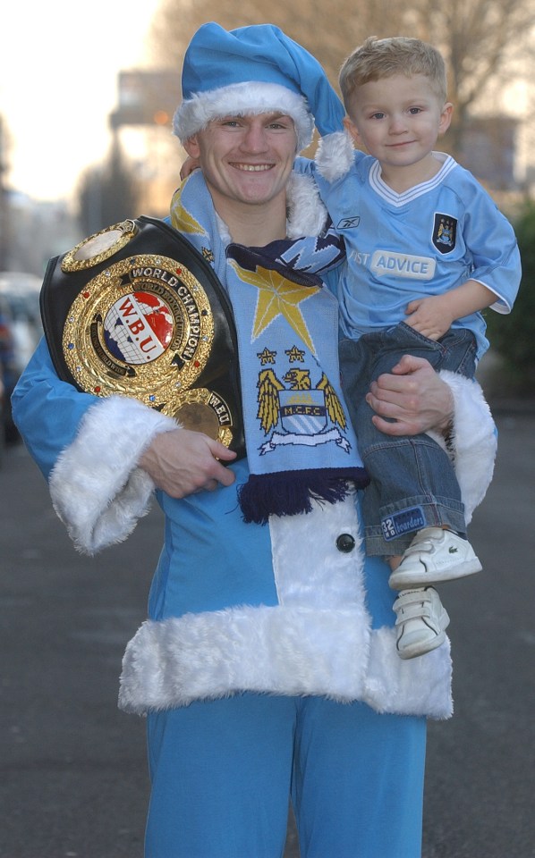 Ricky Hatton, in a Santa suit, holds his son and a boxing championship belt.