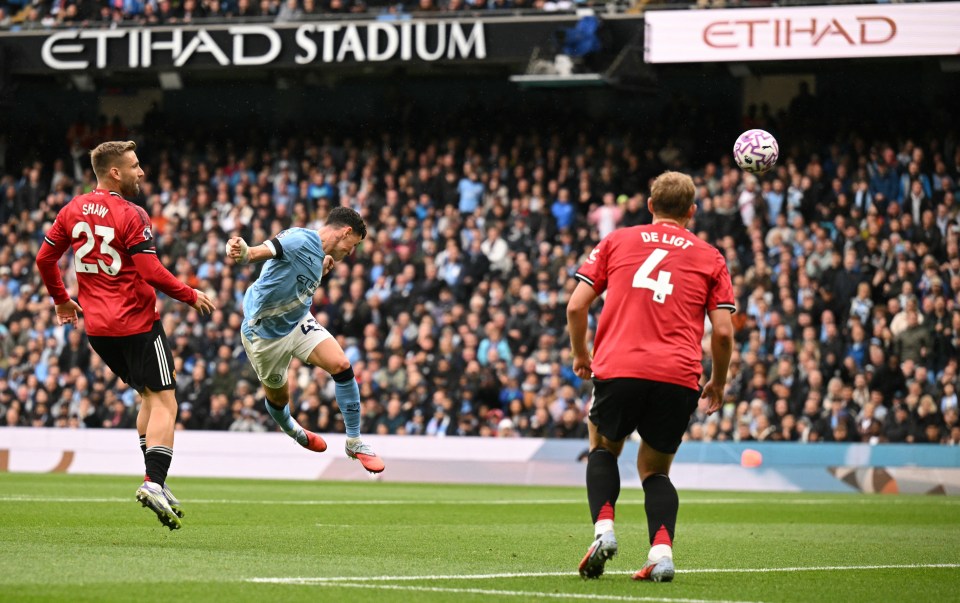 Phil Foden scoring a header during a Manchester City vs Manchester United match.