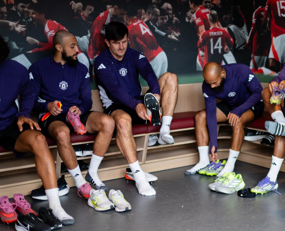 Manchester United players putting on their cleats in the locker room.