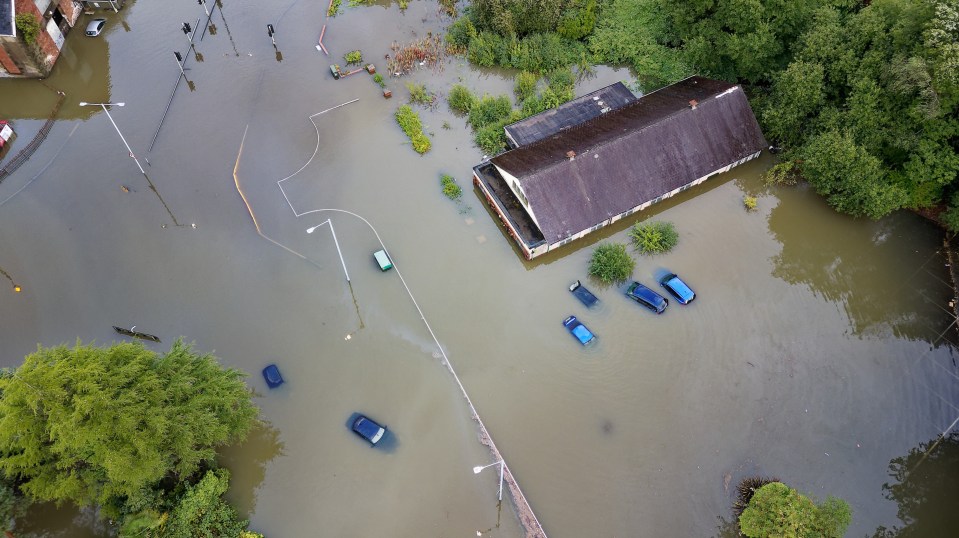 Aerial view of flooded area with submerged cars and buildings.