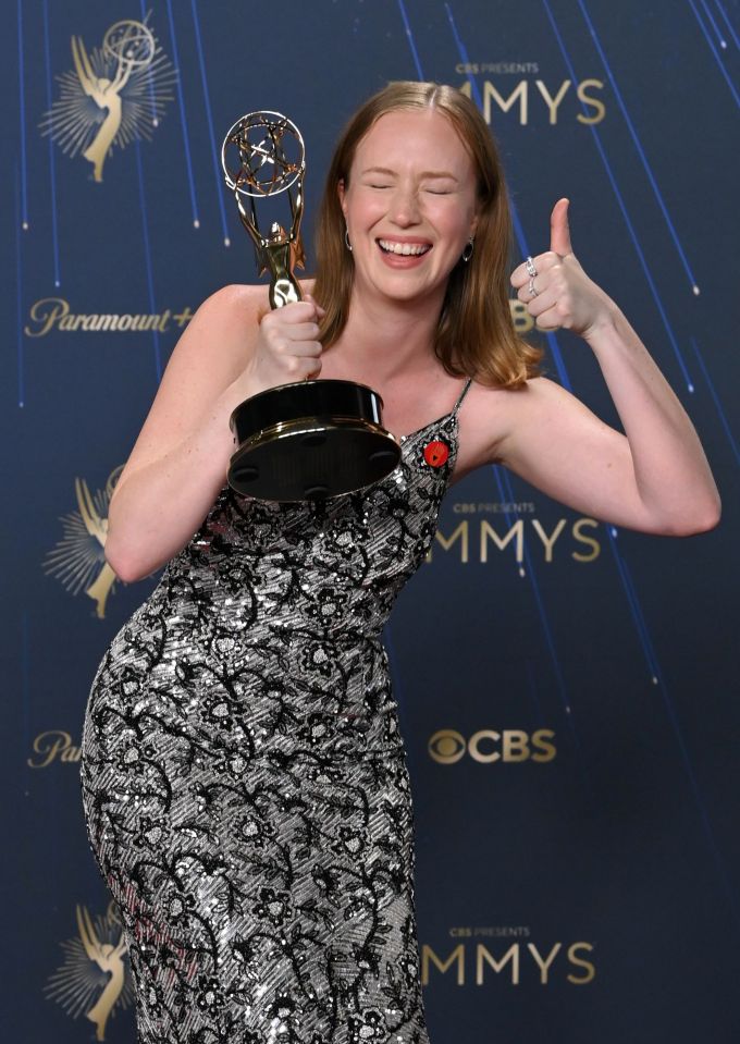 Hannah Einbinder holding an Emmy award and giving a thumbs up.