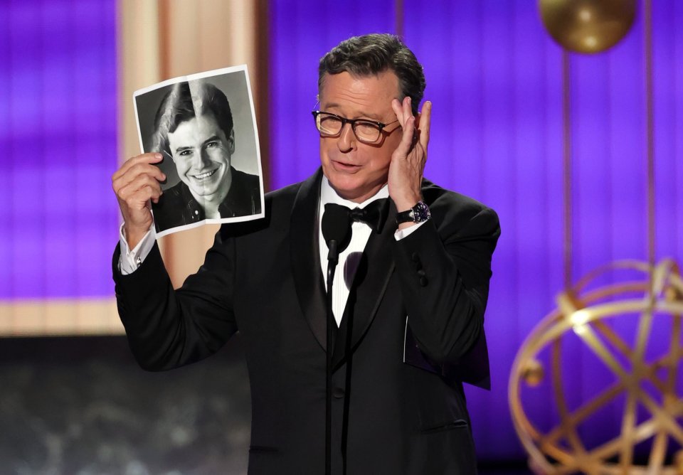 Stephen Colbert at the Emmy Awards holding a photo of his younger self.