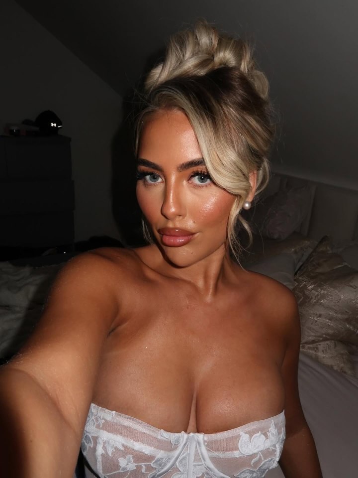 Selfie of a woman in a white lace corset top.