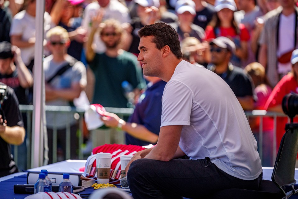 Man in white shirt sitting and speaking to a crowd.