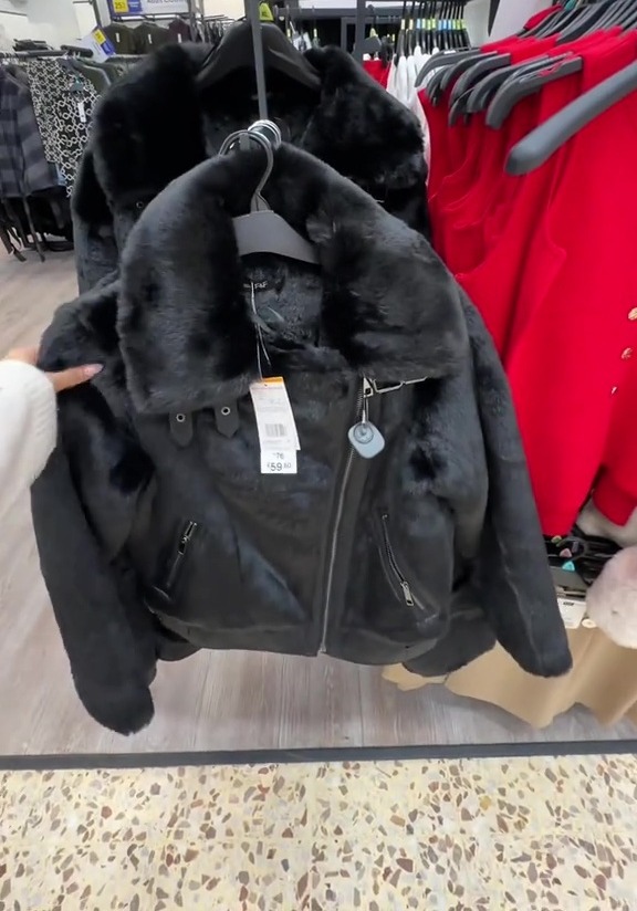 Black faux fur-trimmed jacket on a clothing rack.