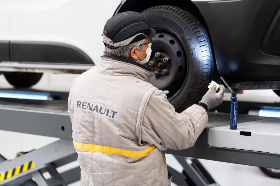 Renault technician inspecting a car at a recycling plant.