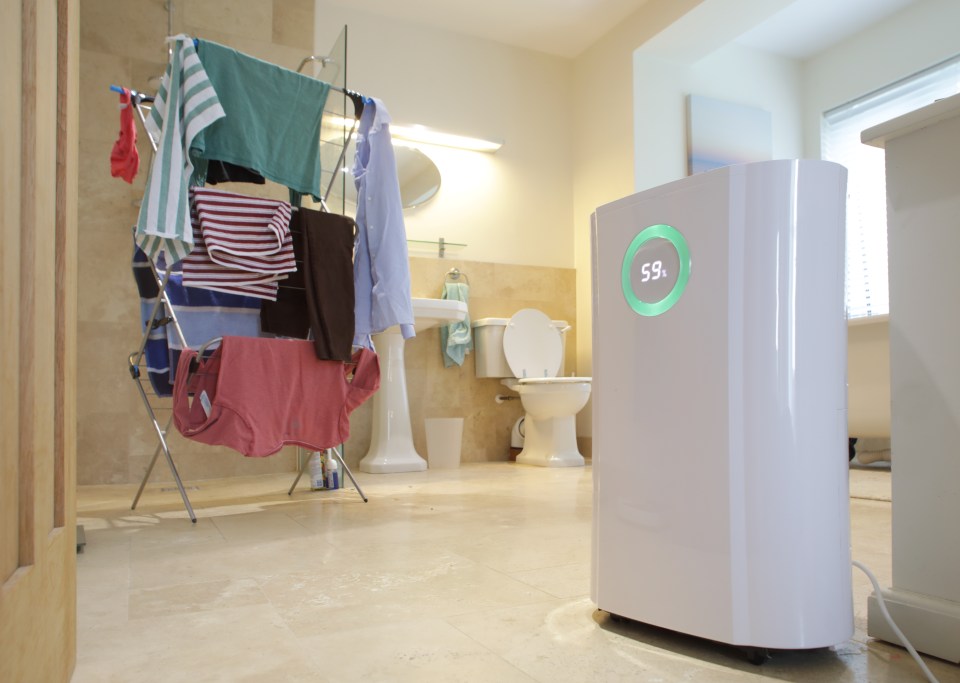 A dehumidifier with a 59% humidity reading drying clothes in a bathroom.