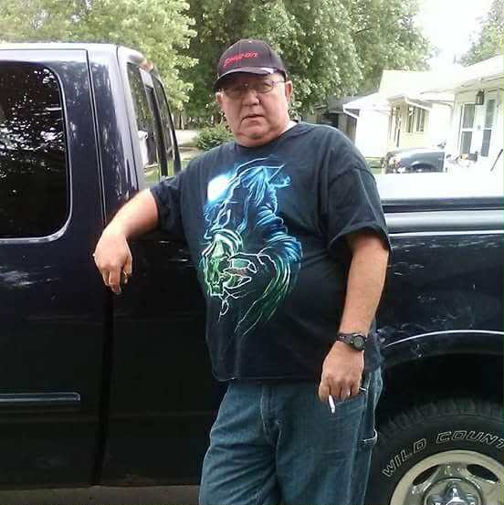 Photo of a man leaning against a truck.