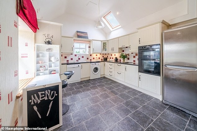 A fuel-burning stove divides the space from the kitchen behind