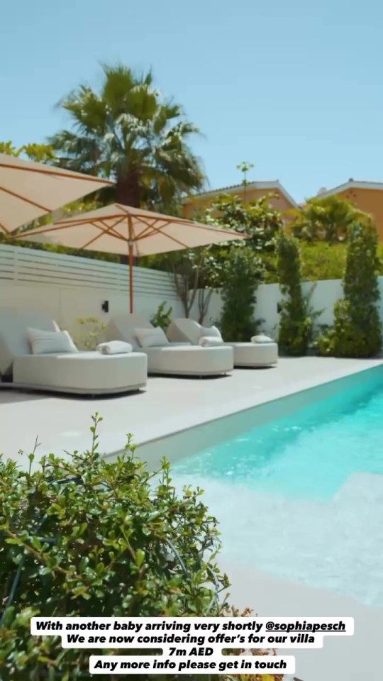 Luxury poolside area with white loungers and umbrellas.