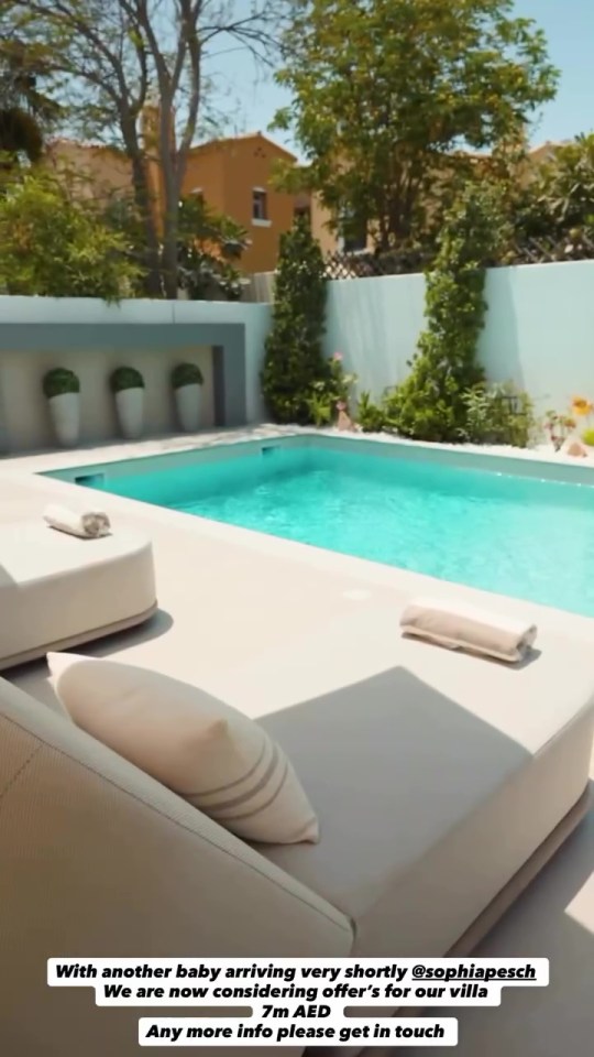 A swimming pool area with lounge chairs and green plants, with a villa for sale in Dubai.
