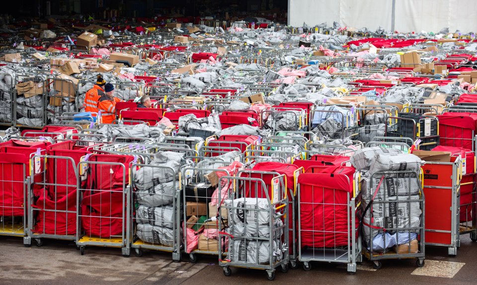 Heaps of Christmas letters and parcels piled up in and around dozens of mail carts outside a Royal Mail center.