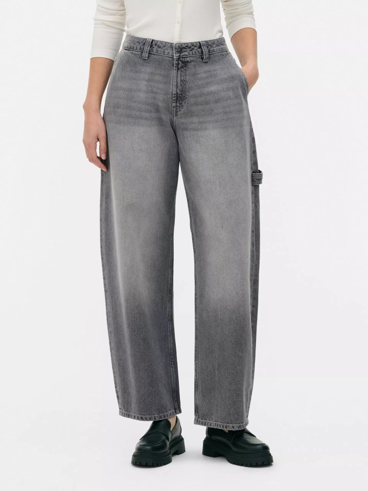 A person wearing loose-fitting gray jeans with thick-soled black loafers.